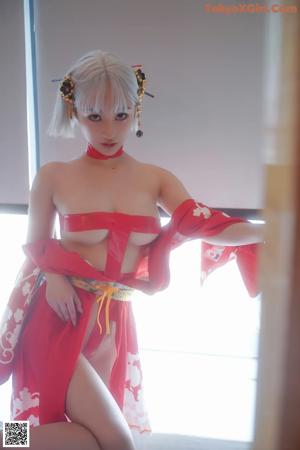 A woman in a red kimono sitting in a bathtub.