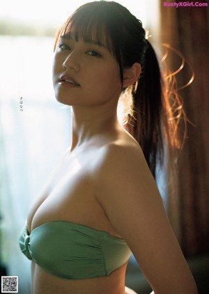 A woman in a white lingerie sitting on a green chair.