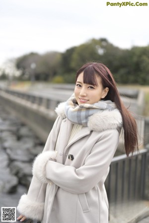 A woman in a school uniform pointing at the camera.