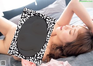 A woman laying on a bed holding up a black and white photo.