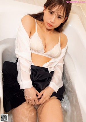 A woman in a black lingerie sitting on a bed.