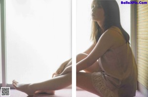 A woman laying on top of a rock next to a wall.