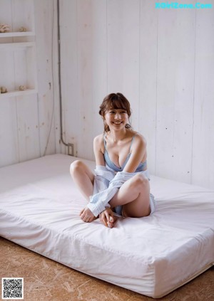 A woman sitting on top of a white bed.