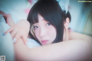 A woman in a pink sweater and striped stockings sitting on a bed.