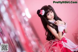 A woman in a pink and black maid outfit is posing for a picture.