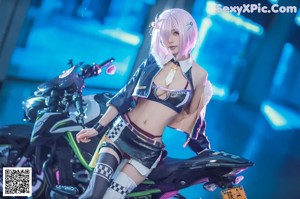 A woman with pink hair sitting on a motorcycle.