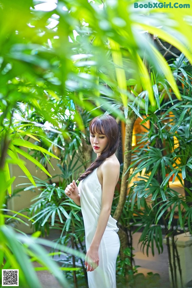 A woman in a white dress standing in a garden.