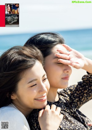 A couple of women laying on top of a bed.