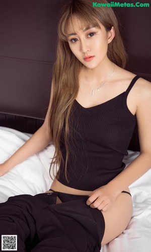 A woman in a black top and black pants posing for a picture.