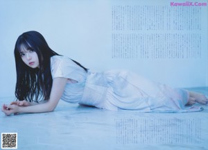 A young woman laying on a bed with her hand on her chin.