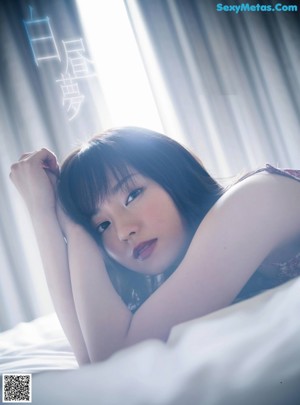A woman sitting on a bed looking out a window.