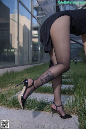 A woman in a black dress and high heels posing for the camera.