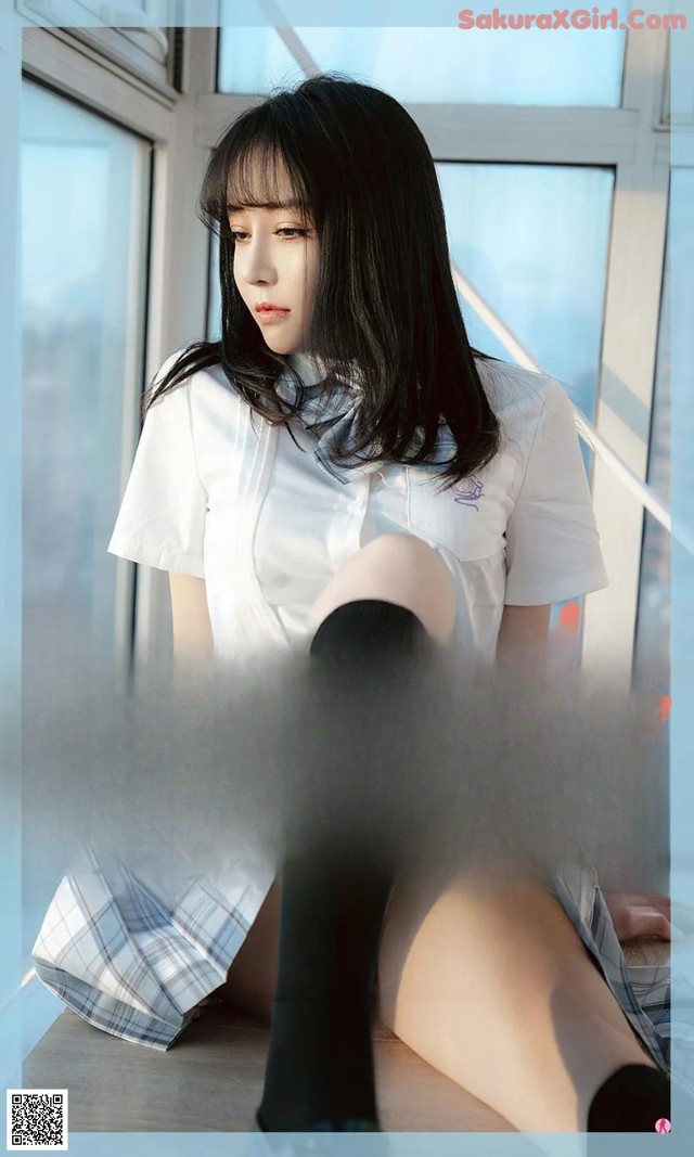 A woman sitting on top of a window sill next to a window.