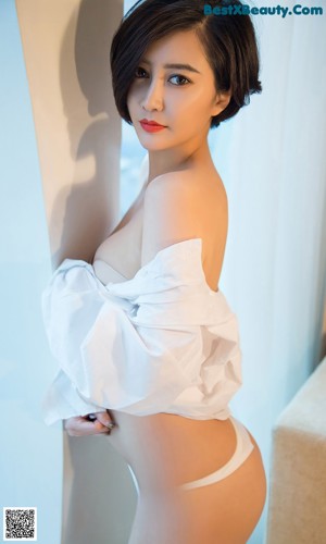 A woman in a black lingerie sitting on a bed.