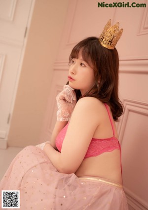 A woman in a pink lingerie with a crown on her head.